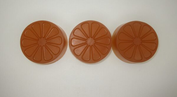 Three orange slices are lined up on a white surface.